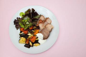 Baked pork with vegetables and fresh salad on plate