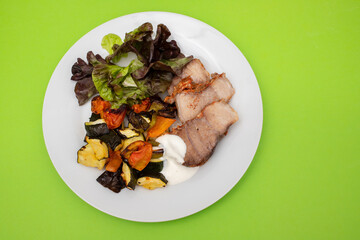 Baked pork with vegetables and fresh salad on plate