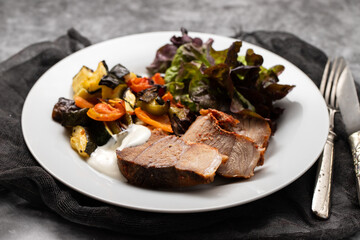 Baked pork with vegetables and fresh salad on plate