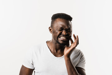 African man with tooth decay, infection or injury to the tooth or gums on white background. African american man is touching cheek and feeling toothache pain and discomfort of tooth.