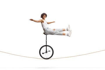 African american male acrobat sitting on a monocycle over a rope © Ljupco Smokovski