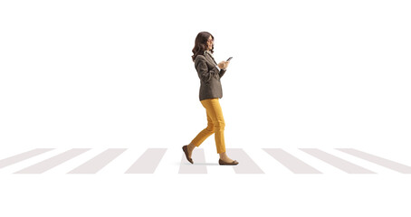 Young woman with a smartphone walking on a pedestrian crossing