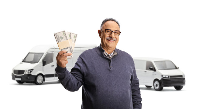 Mature Man Holding Stacks Of Money In Front Of Two White Vans And Smiling