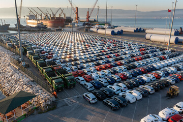 New assorted cars lined up in the port waiting to be loaded on the ro-ro (Roll on Roll off) vehicle car carrier ship. Aerial drone photo - obrazy, fototapety, plakaty