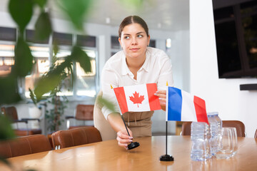 Employee of delegation prepares negotiating table - sets up the flag of Canada and France