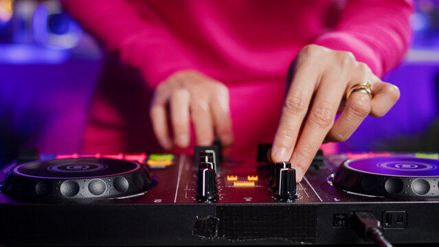 Dj artist creating unique techno sound using mixer console, performing at eletronic party in club at night. Asian musician playing remix song using professional audio equipment. Music concept