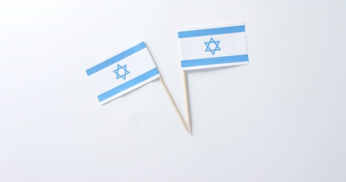 Close up of two flags of israel lying on white background with copy space