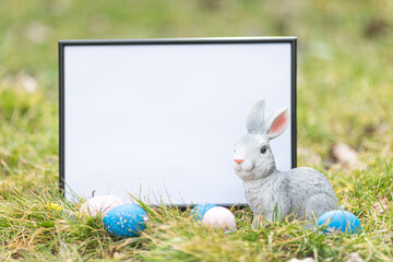 Easter greeting card. Easter bunny and Easter eggs on green grass field spring meadow. Space for text. Mock up