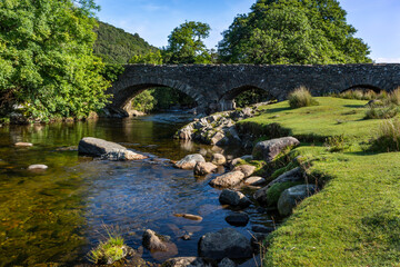 Fototapeta na wymiar The River Duddon flows under the bridge at the picturesque village of Ulpha on the Sella Brow Road in the Lake DistrictNational Park, England.