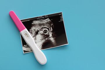 Pregnancy test and baby ultrasound photo scan photo on blue background. Family planning and antenatal care, health check concept.