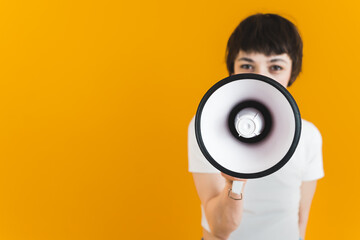 Medium shot of a woman in a white T-shirt holding a loudspeaker before her face. High quality photo