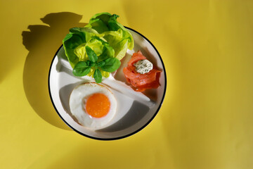 top view of healthy ketogenic breakfast with fried egg, green salad and smoked salmon