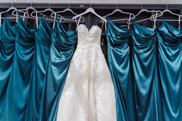 Bridesmaid's dress, white wedding dress hanging next to blue bridesmaid dresses