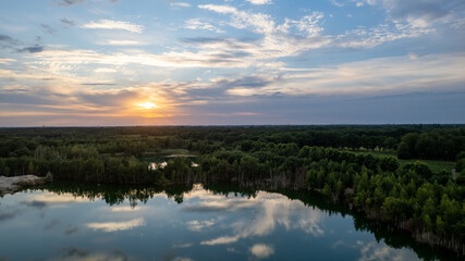 Aerial panorama Early Sunrise over forest lake. Noctilucent night clouds, summer foggy lake reflects sky. High quality photo