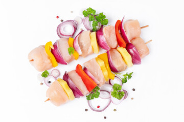 Raw pieces of chicken skewers with pepper onion and pineapple on a white background.Uncooked mixed meat skewer with peppers.Skewers with pieces of raw meat, red, yellow and green pepper.Top view.