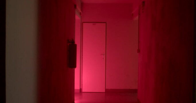 The scene of the crime in the corridors of the basement. Locked door, flashing police light, red blue light. Fire extinguisher silhouette on the wall.