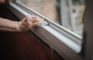 Obraz premium Hands of a Caucasian man cleans the window frame.