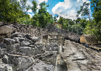 Fototapeta na wymiar Mayan ruins and hut on bottom of the pyramid known as The Church structure, 600-900 A.D. in Coba, Quintana Roo, Yucatan, Mexico
