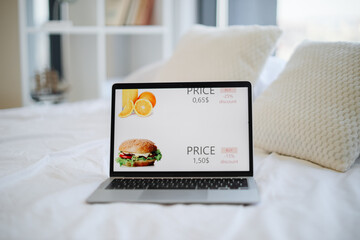 Modern wireless laptop with online shop selling fresh orange juice with 25 percent discount and tasty burger with 15 percent discount. Concept of sale, consumerism and shopping.