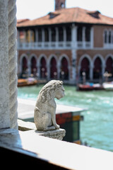 small sculpture of a lion against the backdrop of the grand canal in venice, palace in italy