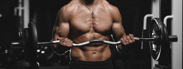 Fototapeta na wymiar Muscular guy, fitness model, bodybuilder posing after training in the gym