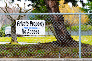 A large white sign on a chain link fence which indicates this is private property with no...