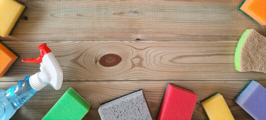 Banner with cleaning products in house. Flat lay. Place for text. Cleaning Products for Sparkling Home. Variety of sponges and spray for cleaning surfaces on wooden background. Copy space. Top view.
