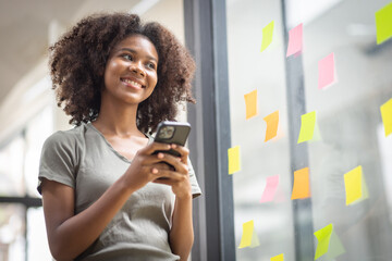A black American african business woman in afro hairstyle planning in meeting at office and use post it notes to share idea. Brainstorming concept. Sticky note on glass wall.