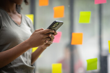 A black American african business woman in afro hairstyle planning in meeting at office and use post it notes to share idea. Brainstorming concept. Sticky note on glass wall.
