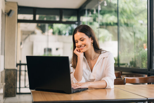 Young smiling latina girl calling on laptop. Cute student looking at computer screen watching webinar or video chatting on webcam