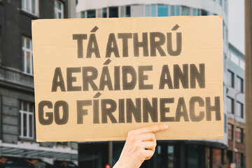 The phrase " Climate change is real " drawn on a carton banner in men's hands. Sustainability. Emissions. Renewable. Conservation. Adaptation. Carbon. Ocean. Atmosphere. Recycling. Drought. Melting