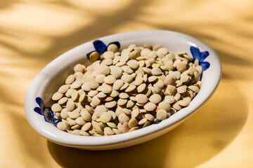 stack of lentils on a plate on a yellow background, view from above