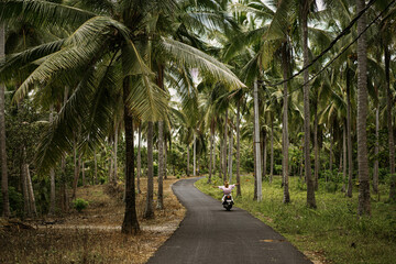 Young woman on a motorbike on the tropical island of Nusa Penida.