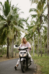 Fototapeta premium Young woman on a motorbike on the tropical island of Nusa Penida.