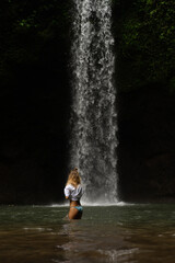 Fototapeta premium Woman tourist at a waterfall in the tropical jungle, Bali.