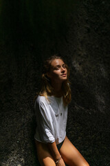 Naklejka premium Woman tourist at a waterfall in the tropical jungle, Bali.