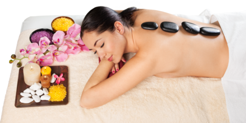 Beautiful young woman receiving hot stone massage at salon spa