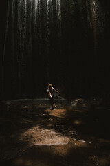 Woman tourist at a waterfall in the tropical jungle, Bali.