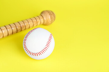Wooden baseball bat and ball on yellow background, space for text. Sports equipment