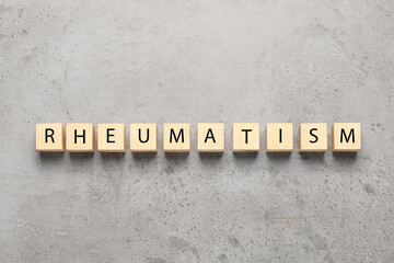 Word Rheumatism made of wooden cubes on light gray textured background, top view