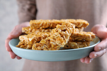 Woman holding plate with delicious peanut kozinaki bars, closeup