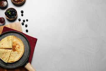 Delicious crepes with blueberries and mint on light grey table, flat lay. Space for text