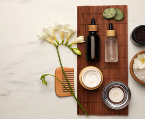 Fototapeta na wymiar Flat lay composition with different spa products and flowers on white marble table