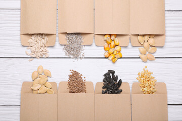 Many different vegetable seeds on white wooden table, flat lay