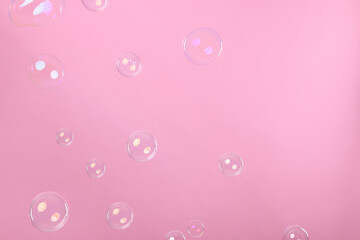 Many beautiful soap bubbles on pink background
