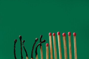 Burnt and whole matches on green background, space for text. Stop destruction concept