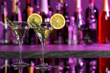 Martini glasses of refreshing cocktail, lemon slices and rosemary on mirror surface, space for text