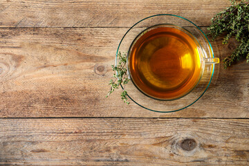 Aromatic herbal tea with thyme on wooden table, flat lay. Space for text