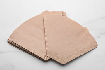 Paper coffee filters on white marble table, above view