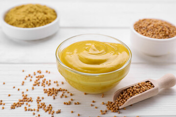 Bowl with delicious mustard and seeds on white wooden table